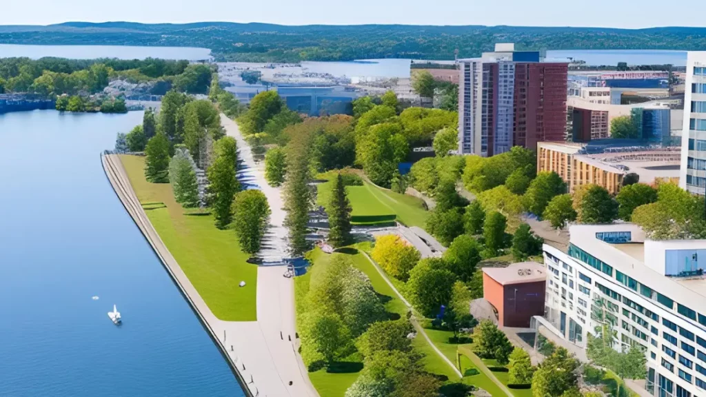 Overhead view of the Burlington Waterfront Trail with the shimmering Lake Ontario on one side and lush green foliage on the other, extending towards the bustling Burlington cityscape.