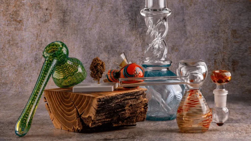 Colorful assortment of bongs, water pipes, and bubblers placed on a rustic wooden surface