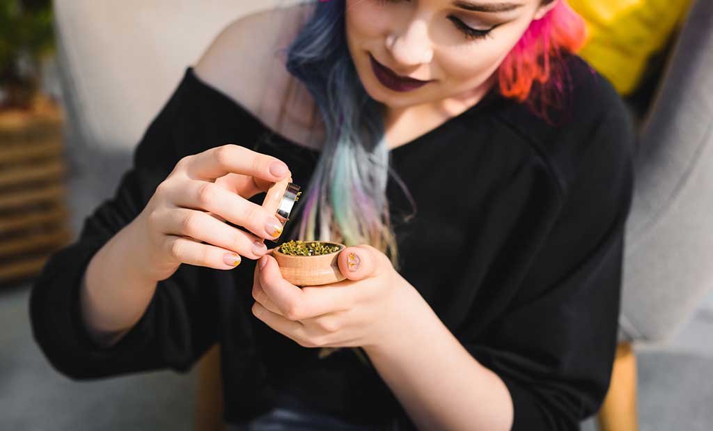 burlington female grinding cannabis in a grinder purchased from a weed store near me in Burlington.